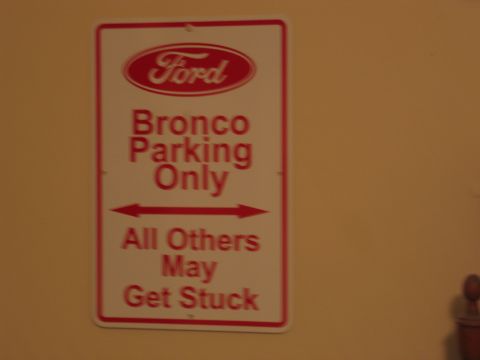 1995 Ford Bronco - A sign indicates that parking is reserved for Ford Broncos, with a humorous warning for other vehicles.