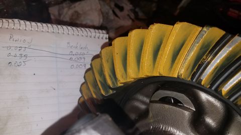 1985 Ford Bronco - A close-up shot shows a differential ring gear with yellow marking compound on its teeth, next to a notebook with handwritten measurements…