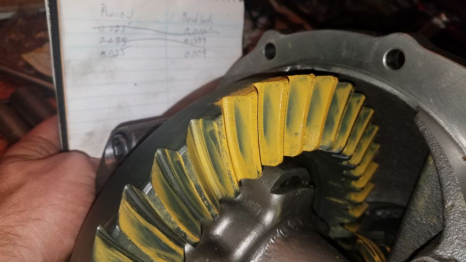 Differential ring gear teeth with yellow marking compound and a notebook with measurements.