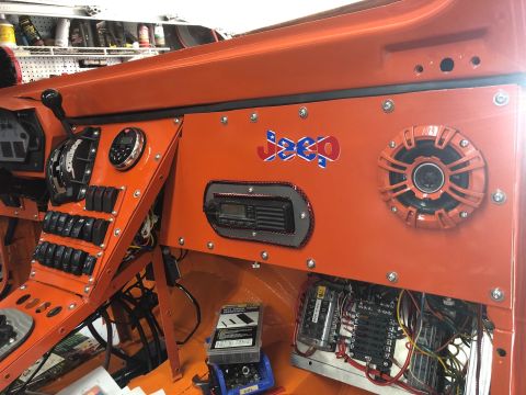 1992 Jeep Wrangler - The interior dashboard of an orange vehicle features a collection of toggle switches, a marine radio, a speaker, and a custom decal with th…