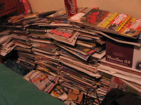1995 Ford Bronco - A large collection of magazines is piled up, with a Coca-Cola can visible on top.