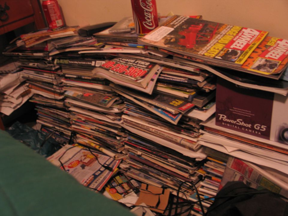 Stack of magazines and a Coca-Cola can on a shelf