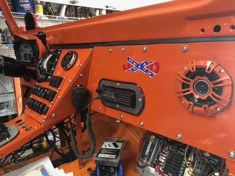 1992 Jeep Wrangler - The interior dashboard of an orange Jeep Wrangler features numerous toggle switches, a CB radio, a speaker, and a "Jeep" logo with a Confed…