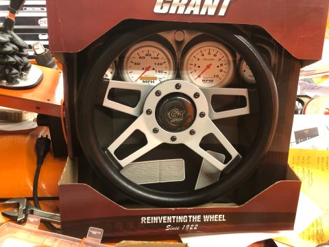 1992 Jeep Wrangler - A Grant steering wheel with integrated gauges is displayed in its retail packaging. The packaging has text that reads "REINVENTING THE WHEE…