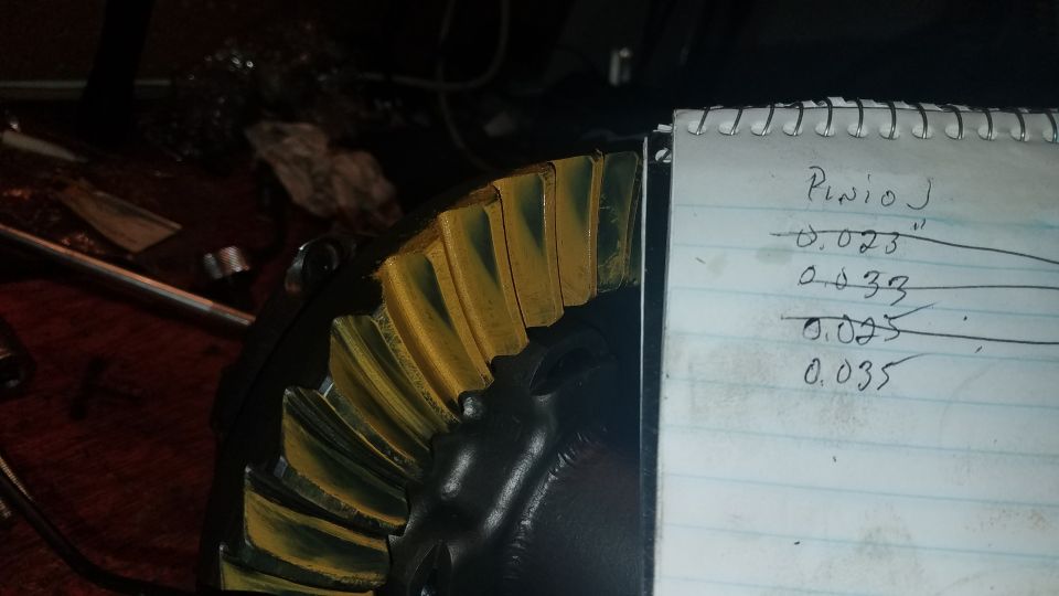 Differential ring gear with yellow marking compound and a notepad with measurements.