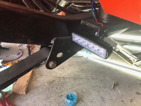 1992 Jeep Wrangler - A close-up view shows a black LED light bar mounted to the underside of a vehicle's frame, with red and blue wires connected to it. A leaf…