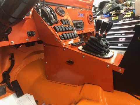 1992 Jeep Wrangler - The interior of an orange Jeep Wrangler shows a custom dashboard with multiple toggle switches, gauges, and a triple-stick shifter setup. V…