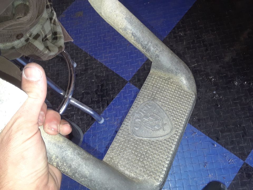 Close-up of a textured metal step with a triangular emblem.