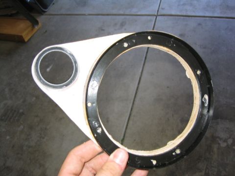 1989 Ford Bronco - A hand holds up a custom white fiberglass speaker pod baffle over a concrete garage floor, with a large black MDF mounting ring bonded arou…
