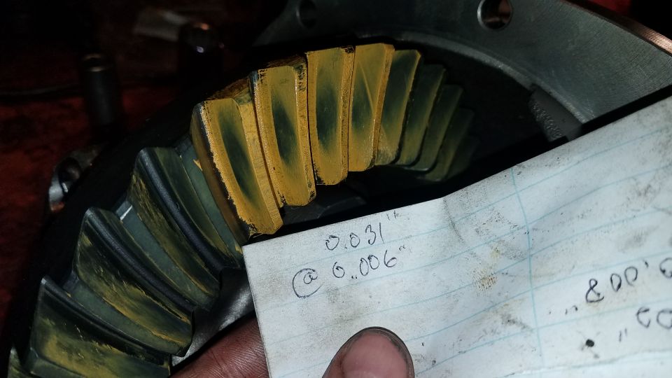 Differential gears with yellow marking compound and handwritten measurements on paper.
