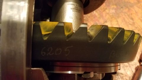 1985 Ford Bronco - A close-up view of a differential ring gear with yellow marking compound on its teeth. White handwritten numbers "6205" are visible on the…