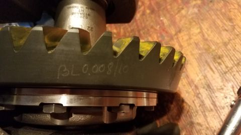 1985 Ford Bronco - A close-up view of a differential ring gear with hand-written markings "BL 0.008/10" is visible on its surface. The gear has yellow marking…