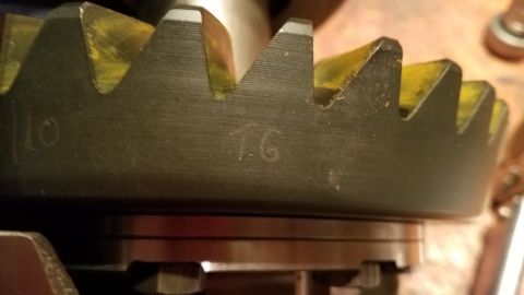 1985 Ford Bronco - A close-up view of a black ring gear with yellow teeth, showing stamped numbers '10' and '16'. The gear appears to be part of a vehicle's d…