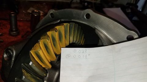 1985 Ford Bronco - A close-up view of a differential with gear teeth showing wear patterns. A piece of paper with handwritten measurements is placed over the…