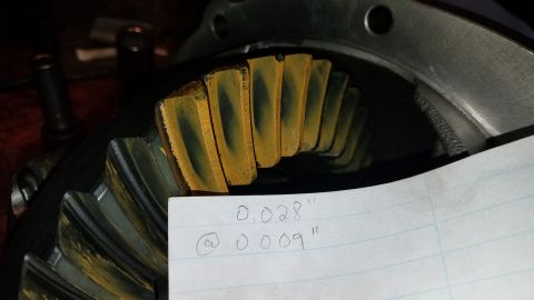 1985 Ford Bronco - A close-up view shows the teeth of a ring gear with yellow and blue wear pattern indicating contact. A piece of paper with handwritten meas…