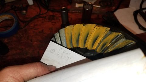 1985 Ford Bronco - A close-up view of a differential ring gear with yellow marking compound on its teeth. A handwritten note with measurements "0.028" and "0.…