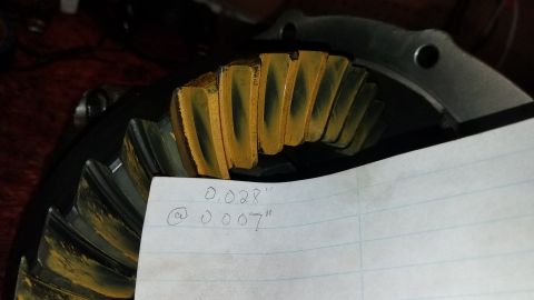 1985 Ford Bronco - A close-up view of a differential gear with yellow-orange wear pattern on the teeth. A piece of paper with handwritten measurements '0.028"…