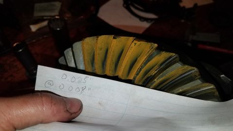 1985 Ford Bronco - A close-up of a differential gear with yellow marking compound on its teeth. A piece of paper in the foreground has handwritten measurement…