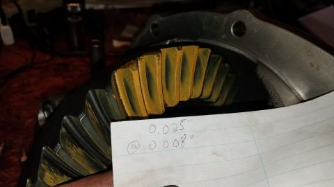 1985 Ford Bronco - A close-up view of a differential gear with yellow marking compound applied to the teeth. A piece of paper with handwritten measurements of…