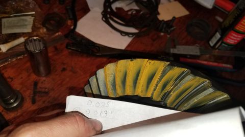 1985 Ford Bronco - A close-up shot shows a ring gear with yellow marking compound applied to its teeth, indicating contact points. A piece of paper with handw…