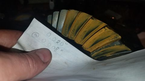1985 Ford Bronco - A close-up shot shows a hand holding a piece of paper with handwritten measurements next to a differential gear. The gear has a yellow-brow…