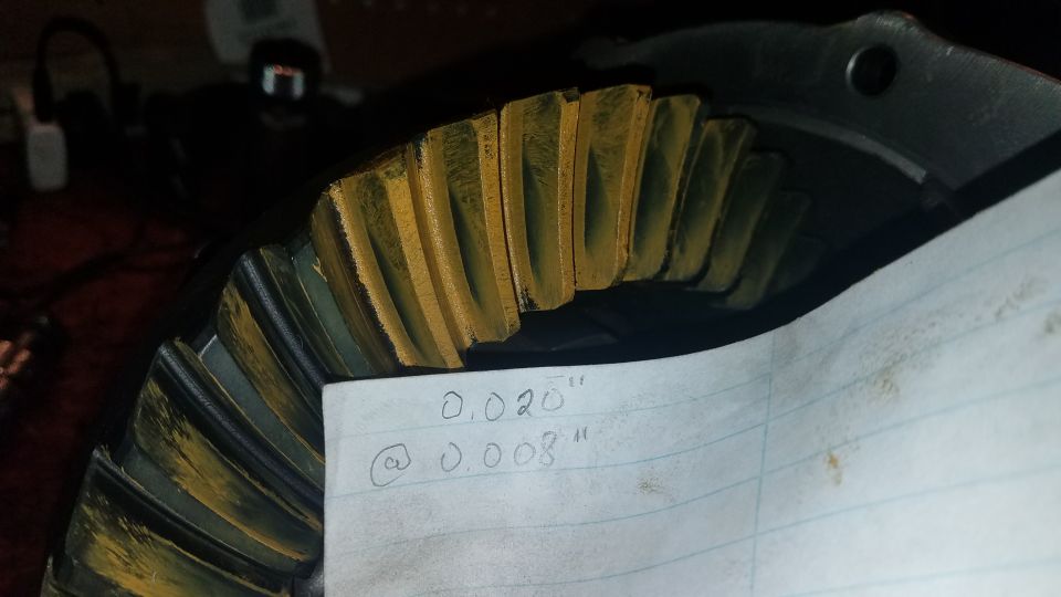 Differential gear with yellow marking compound and handwritten measurements on paper.