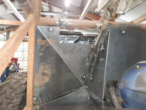 1985 Toyota Hilux - A close-up view of a custom-built vehicle's interior, showing a metal firewall, steering column components, and a portion of the engine. Th…