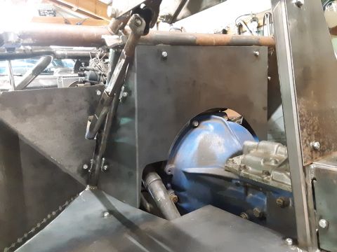 1985 Toyota Hilux - A close-up view of custom metal fabrication around a vehicle's transmission and steering column. The blue transmission housing is visible,…
