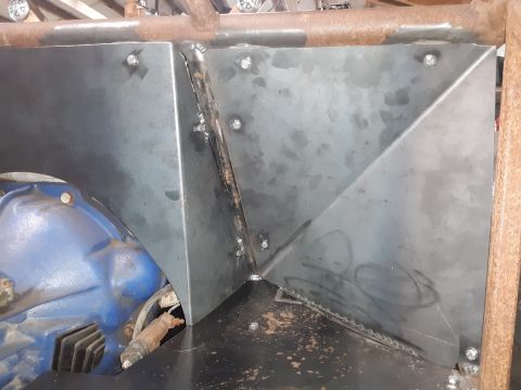 1985 Toyota Hilux - A custom metal fabrication is bolted and welded onto a vehicle's frame, partially obscuring a blue engine component. The metalwork appears…