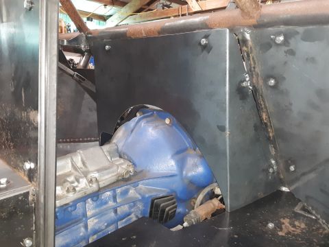 1985 Toyota Hilux - A close-up view of a blue transmission housing and silver transfer case, surrounded by custom metal fabrication, likely in a workshop setti…