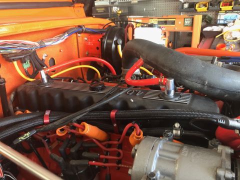 1992 Jeep Wrangler - Close-up view of the engine bay of an orange Jeep Wrangler, showcasing the 4.0L engine valve cover, wiring, hoses, and various engine compo…