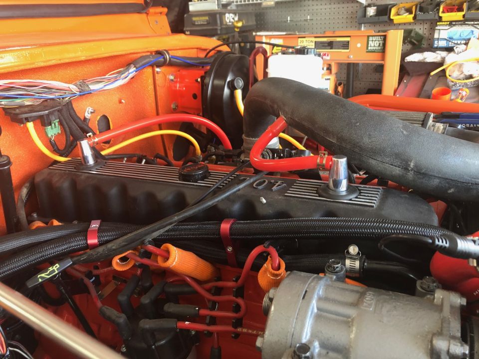 Orange Jeep Wrangler engine bay with 4.0L valve cover, wiring, and hoses.