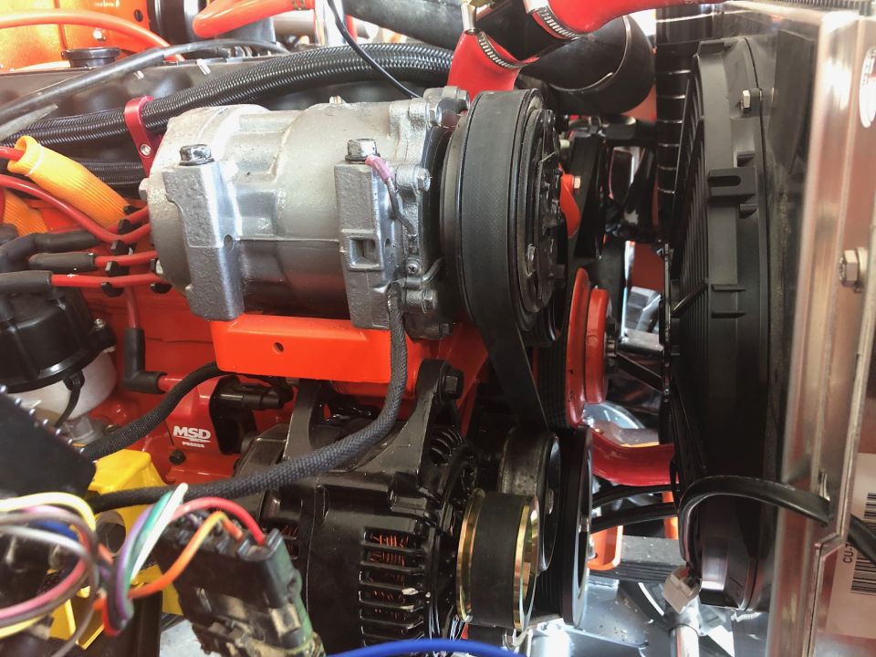 Close-up of Jeep Wrangler engine bay showing AC compressor, alternator, and fan.