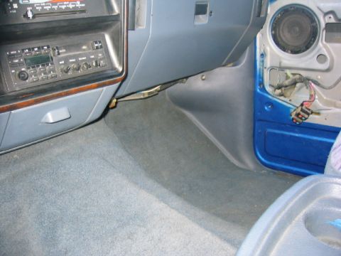 1989 Ford Bronco - Passenger-side footwell and open door with the door trim panel removed, exposing the blue painted door shell, a factory door speaker and a…