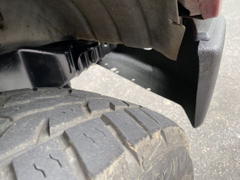 1994 Ford Bronco - A close-up view of the rear tire and fender flare of a vehicle, showing the tread pattern of the tire and the textured black fender flare.