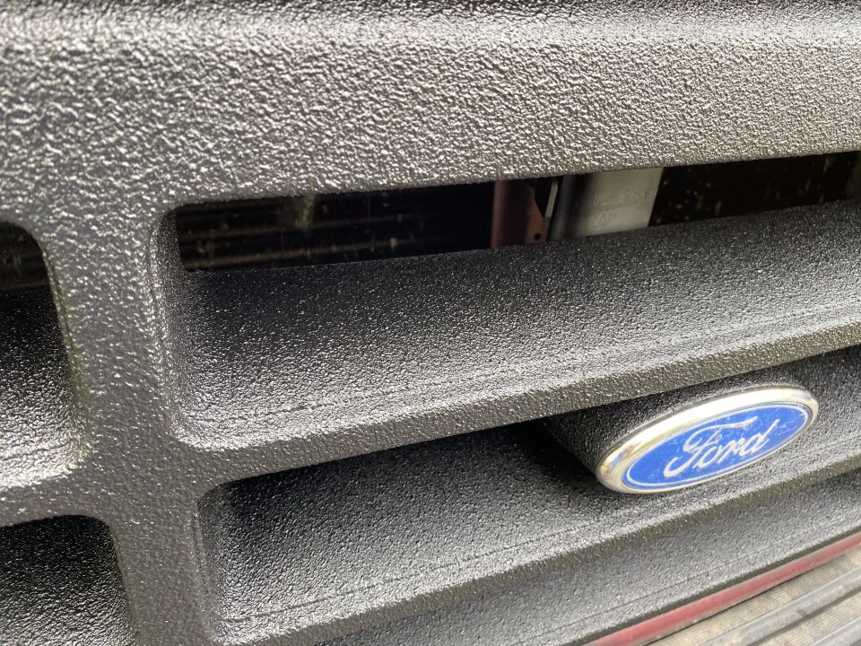 Close-up of a black textured Ford Bronco grille with Ford emblem.