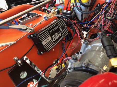 1992 Jeep Wrangler - A close-up view of an engine bay with an orange painted firewall, showing a black MSD Digital 6AL ignition control box and a complex wiring…