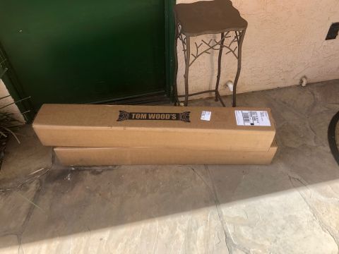 1992 Jeep Wrangler - Two long cardboard boxes are stacked on a stone patio in front of a dark green door. The top box has a black logo that says "TOM WOOD'S" in…