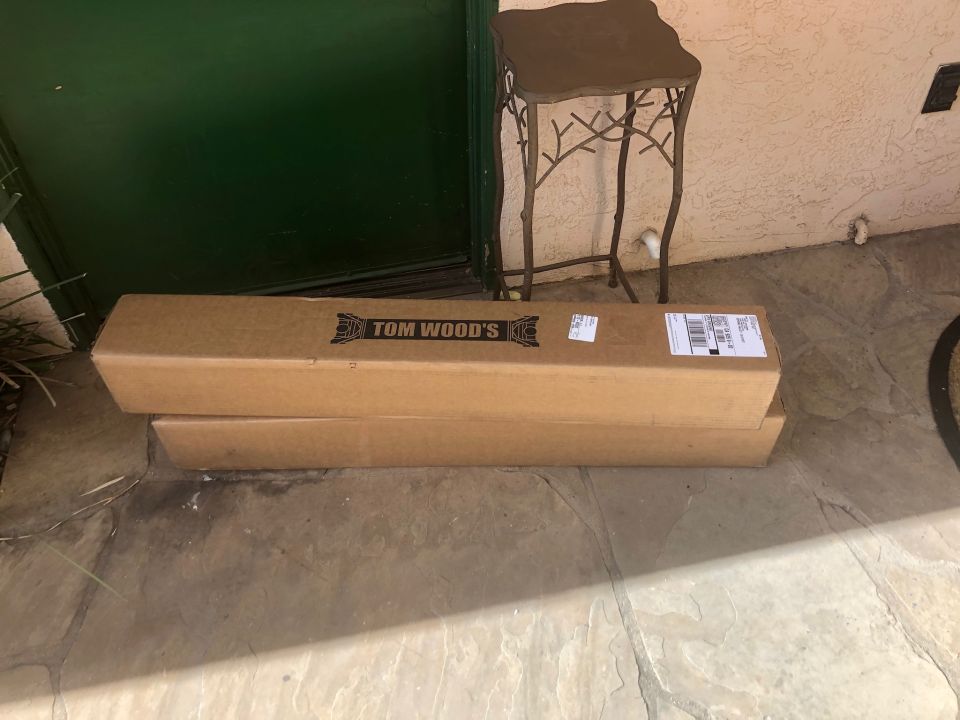 Two cardboard boxes with "TOM WOOD'S" logo stacked on a patio.