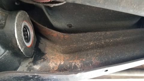 1985 Ford Bronco - A close-up view of the underside of a vehicle, showing a metal suspension component with a bearing and signs of rust and dirt. The angle is…