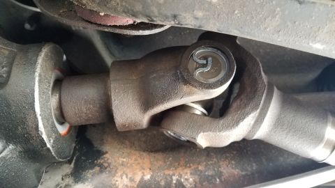 1985 Ford Bronco - A close-up view of a U-joint on a vehicle's driveshaft, showing the connection between two metal shafts. The U-joint appears to be made of…