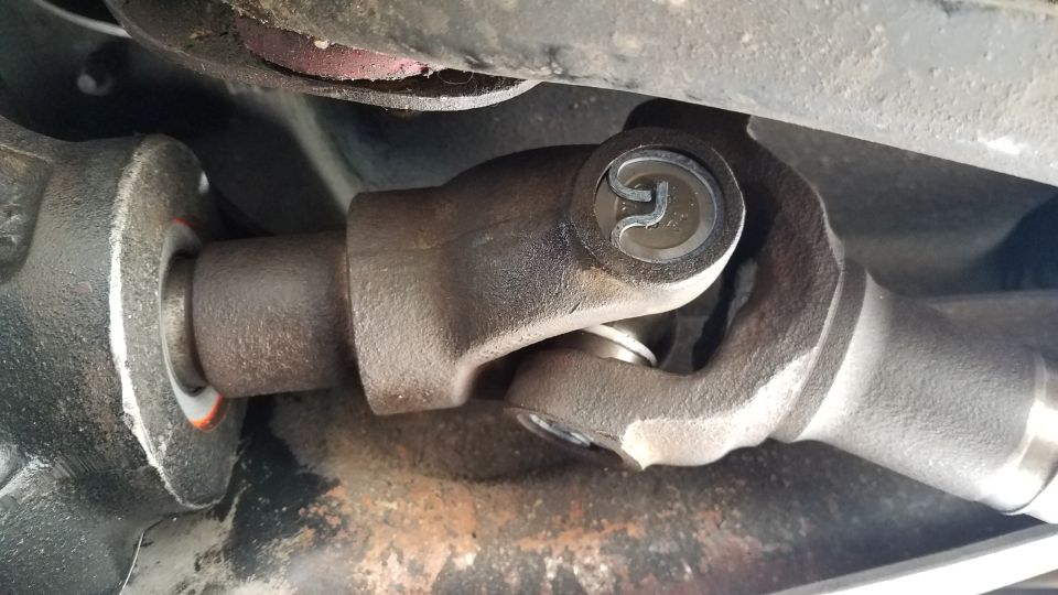 Close-up of a vehicle's driveshaft U-joint connection.