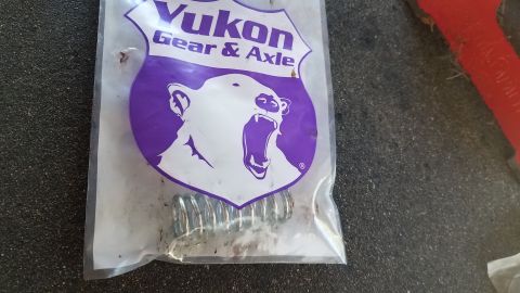 1985 Ford Bronco - A clear plastic bag with the Yukon Gear & Axle logo, featuring a polar bear, contains several metal springs. The bag is resting on a dark,…