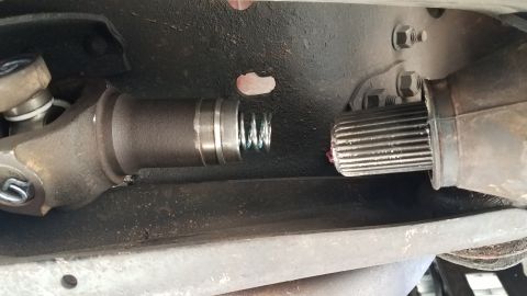 1985 Ford Bronco - A close-up view of a driveshaft slip yoke and companion flange connection, showing the splines and a spring mechanism with grease. The comp…