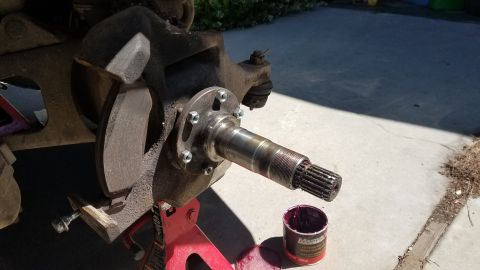 1985 Ford Bronco - A close-up view of a vehicle's front wheel hub assembly, with brake components and a greased spindle visible. A can of red grease sits on t…