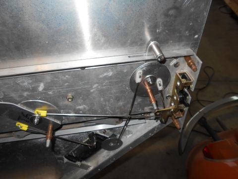 1992 Ford Bronco - Close-up view of the internal mechanism of a vehicle, showing cables, pulleys, and a latch assembly attached to a metal panel.