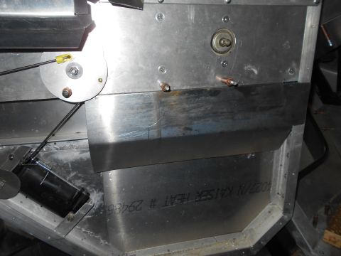 1992 Ford Bronco - A close-up view of a metal component with a cable mechanism and a black cylindrical part attached. Text is visible on the lower metal panel.