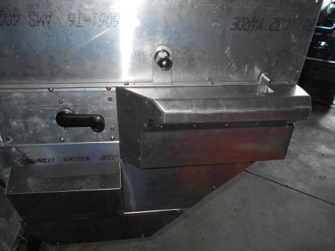 1992 Ford Bronco - A close-up view of the rear of a custom metal fabrication, possibly for a vehicle, showing a black handle, a small metal spout, and stamped…