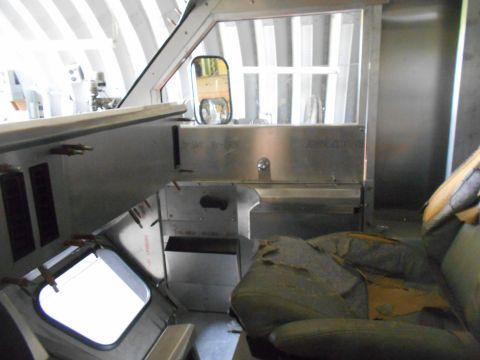1992 Ford Bronco - Interior view of a vehicle's cockpit area, showing a worn driver's seat, a dashboard with various components, and a side mirror reflecting…