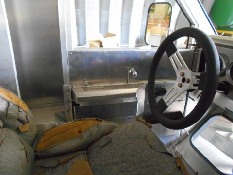 1992 Ford Bronco - The interior of a vehicle shows a worn driver's seat and a steering wheel. The dashboard and console appear to be made of brushed metal.